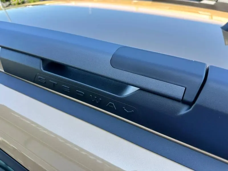 Gros plan sur une barre de toit noire marquée Stepway sur un Dacia Sandero beige Safari, vue extérieure.