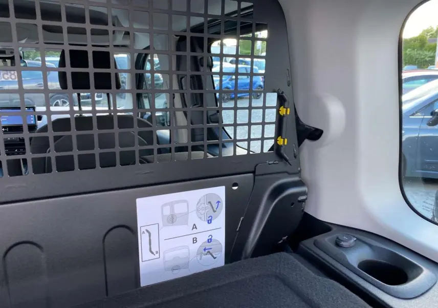 Intérieur arrière du Citroën Berlingo bleu 2025, vue sur la grille de séparation et la fenêtre latérale droite.