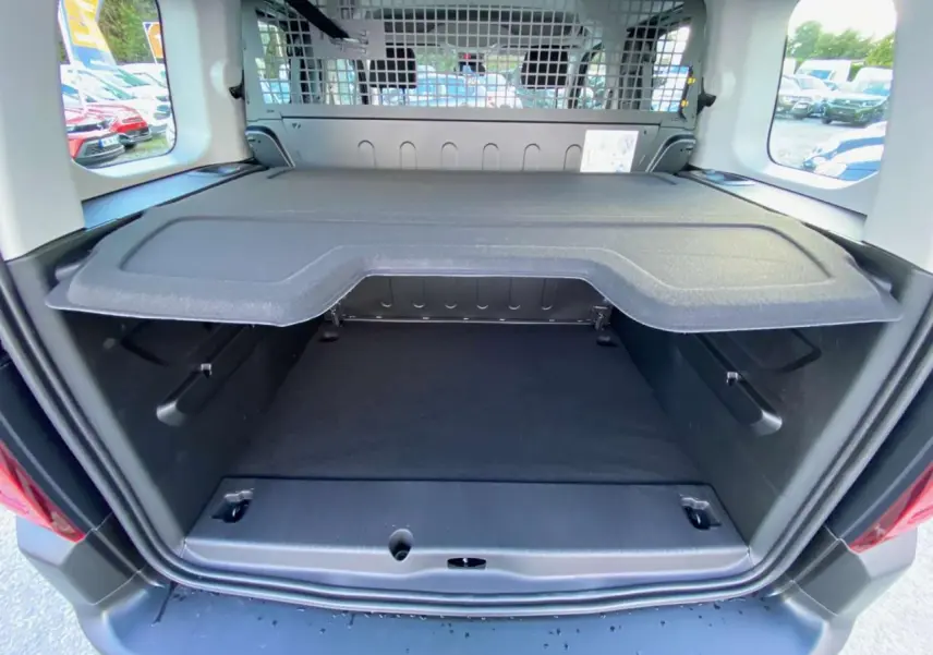 Vue arrière du coffre ouvert d'un Citroën Berlingo bleu 2025, montrant la séparation intérieure et la grille de protection.