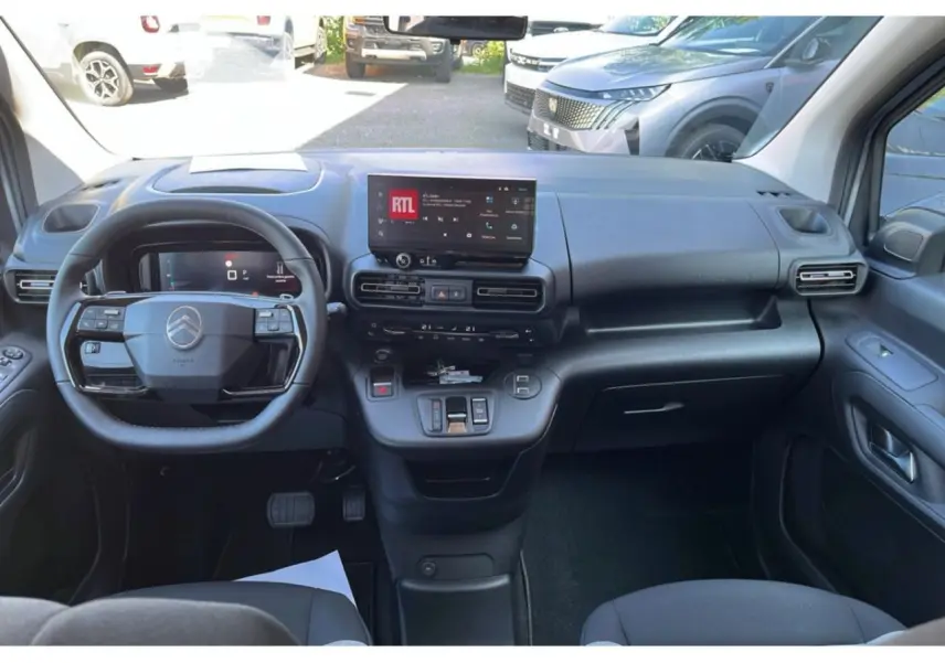 Intérieur du Citroën Berlingo 2025 vu de face, tableau de bord noir avec écran tactile central et volant multifonction.
