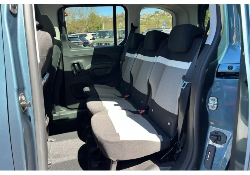 Vue latérale droite sur l'intérieur arrière bleu métallisé du Citroën Berlingo 2025 avec sièges tissu bicolores.