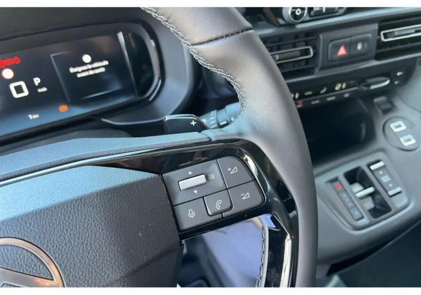 Gros plan sur le volant et le tableau de bord numérique du Citroën Berlingo bleu 2025 avec commandes au volant.