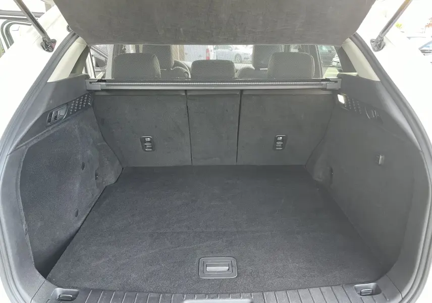 Vue intérieure du coffre spacieux et propre du Mazda CX-60 blanc nacré, avec banquette arrière et cache-bagages visibles.