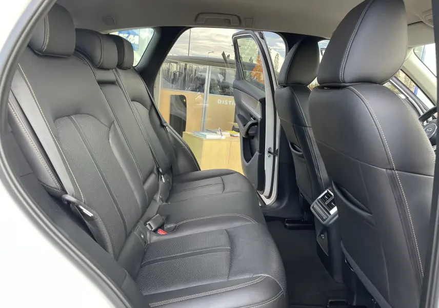 Vue intérieure côté droit montrant les sièges arrière en cuir noir du Mazda CX-60 blanc nacré 2023 avec porte arrière ouverte.