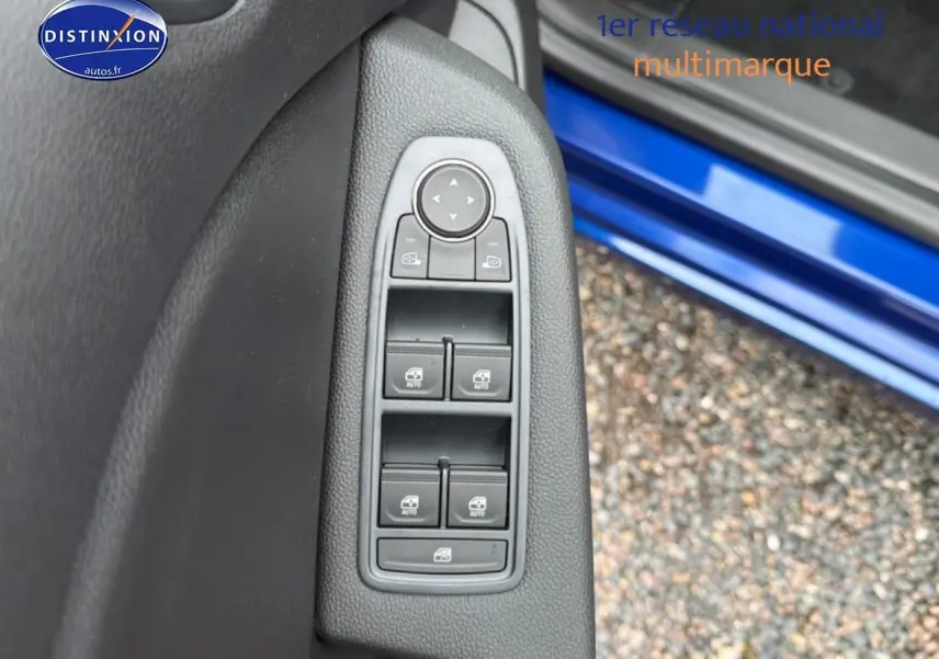 Vue rapprochée des commandes des vitres électriques sur la porte côté gauche d’une Renault Clio V Bleu Iron.