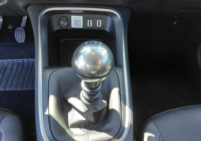 Vue rapprochée du levier de vitesses manuel noir du Jeep Avenger blanc 2025, avec pédales et console centrale visibles.