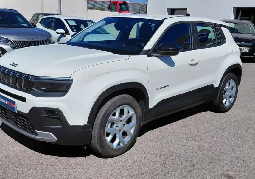 Jeep Avenger blanc en vue 3/4 avant droit, avec calandre noire distinctive et jantes argentées, stationné en extérieur.