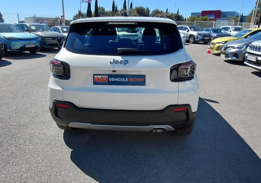 Vue arrière d'un Jeep Avenger blanc 2025 avec feux arrière sombres et plaque "Véhicule récent" sur parking.