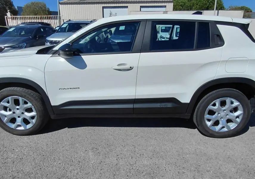 Jeep Avenger blanc en vue de profil côté gauche, avec protections noires sur les bas de caisse et les passages de roues.