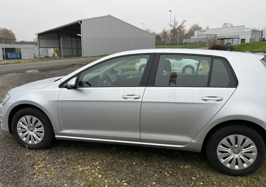 Profil côté gauche d'une Volkswagen Golf 7 argentée de 2017, avec jantes en alliage et carrosserie lisse.