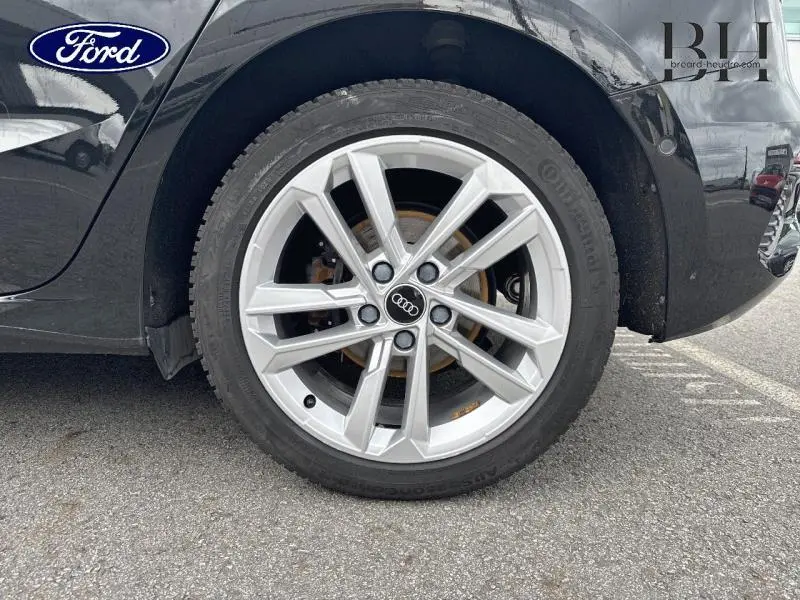 Gros plan sur la jante alu argentée avant droite d’une Audi A3 Sportback noir Mythic métallisé.