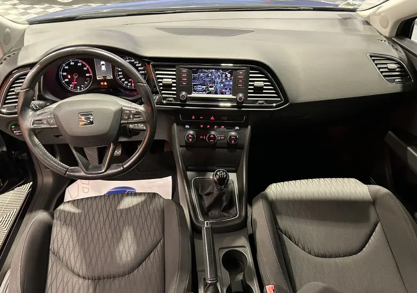 Vue intérieure avant de la SEAT Leon 1.4 TSI 2014, montrant le tableau de bord noir avec GPS et volant cuir multifonction.