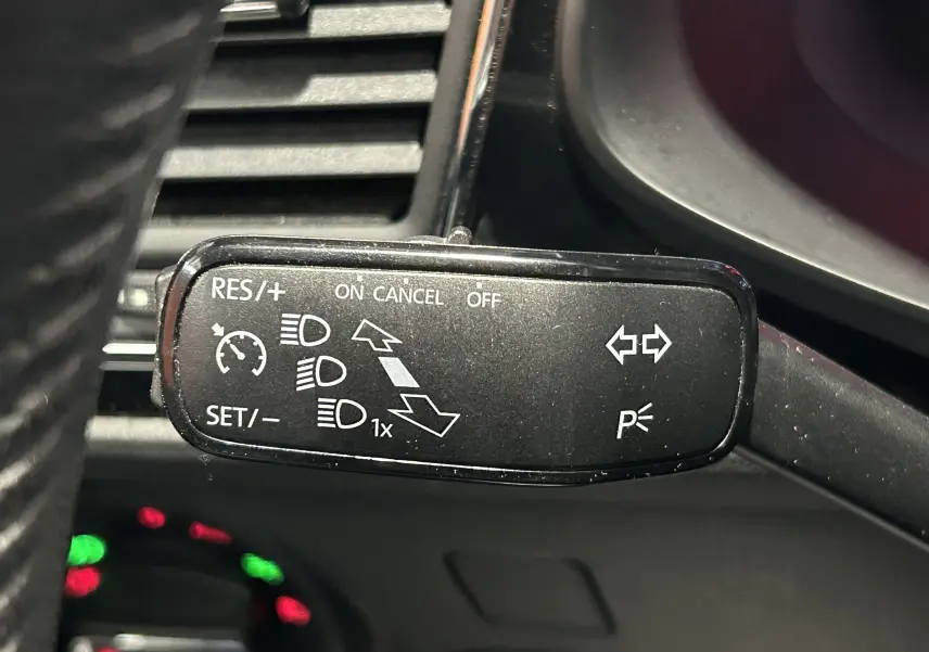 Gros plan sur la manette de commande du régulateur de vitesse et des clignotants dans une SEAT LEON noire de 2014.
