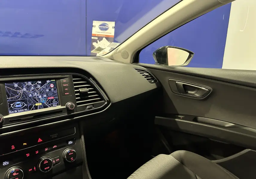 Vue intérieure côté passager du tableau de bord et de la portière d'une SEAT Leon noire, avec écran GPS allumé.