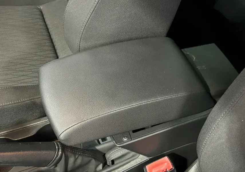 Gros plan intérieur sur l'accoudoir central en cuir noir et siège tissu côté conducteur d'une SEAT Leon 2014.