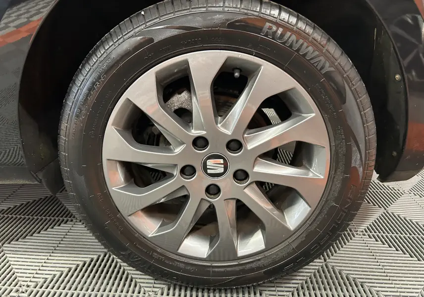 Gros plan sur la roue avant droite d’une SEAT LEON noire de 2014 avec jante alliage et pneu Runway.