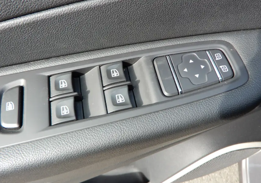 Gros plan sur les commandes de lève-vitres et réglage des rétroviseurs côté conducteur du Renault Captur gris Cassiopée.