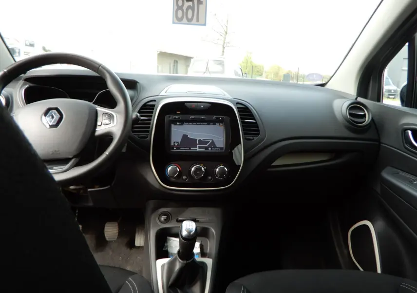 Vue intérieure frontale du tableau de bord du Renault Captur gris Cassiopée, avec écran tactile et levier de vitesse manuel.