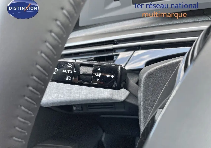Gros plan sur la commande des feux au volant d'un Peugeot 3008 Hybrid bleu Ingaro Metal, intérieur moderne visible.