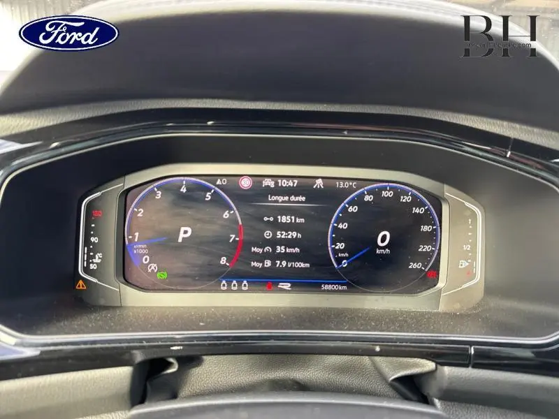 Tableau de bord numérique d'un Volkswagen T-Roc 1.5 TSI bleu, affichant compte-tours et vitesse à 0 km/h.