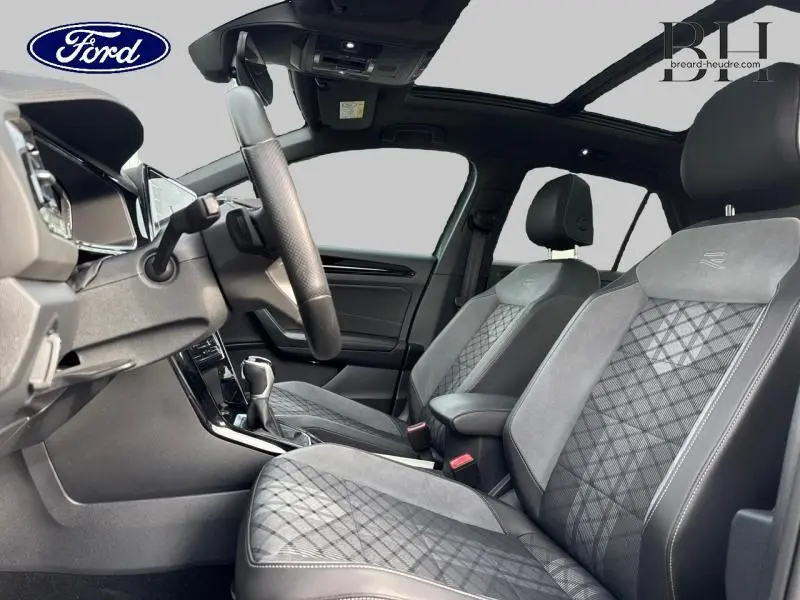 Intérieur avant d'un Volkswagen T-Roc bleu pétrole, sièges R-Line en cuir et alcantara gris avec surpiqûres contrastées.