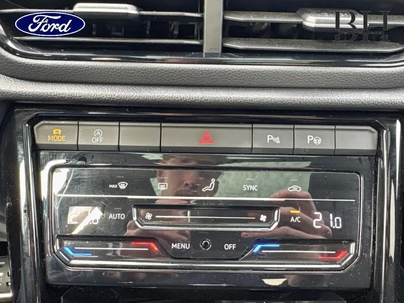 Tableau de bord noir avec commandes climatisation et boutons d'alerte, vue rapprochée intérieure.