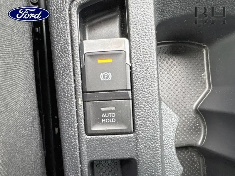 Gros plan sur les commandes de frein de stationnement électronique et Auto Hold dans un Volkswagen T-Roc bleu pétrole 2022.