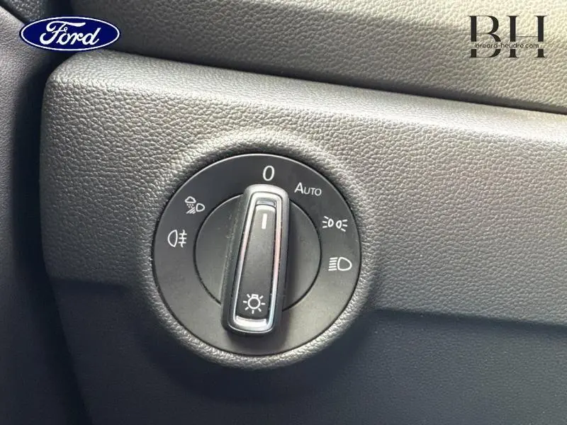 Gros plan sur la molette de réglage des phares dans l'habitacle d'un Volkswagen T-Roc bleu pétrole métallisé.