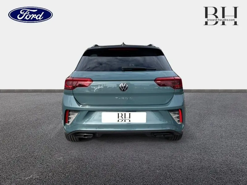 Vue arrière d'un Volkswagen T-Roc bleu pétrole métallisé avec feux arrière LED et double sortie d'échappement chromée.