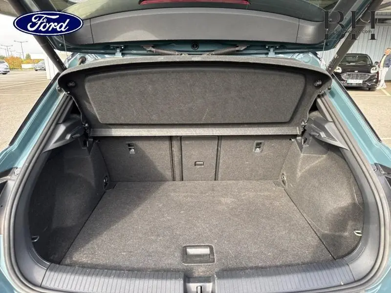Coffre ouvert d'un Volkswagen T-Roc bleu pétrole métallisé, vue arrière montrant l'espace de chargement vide.