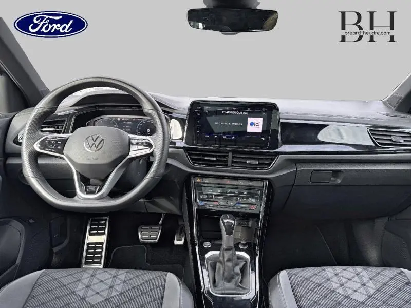 Intérieur avant d'un Volkswagen T-Roc bleu pétrole 2022, volant multifonction et écran tactile central visible.