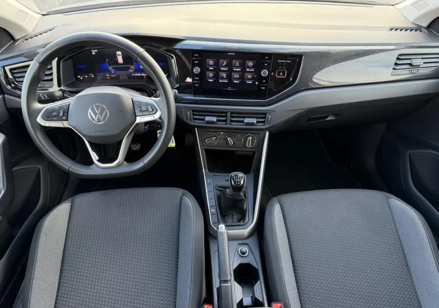 Intérieur de la Volkswagen Polo 2025 en gris, vue de face sur le tableau de bord avec volant et boîte manuelle.