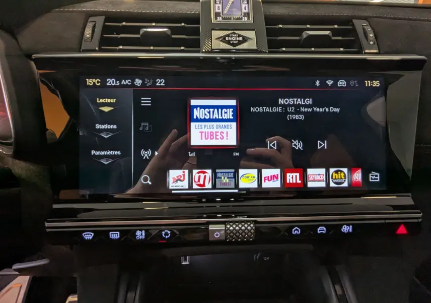 Vue rapprochée de l’écran tactile central du DS7 gris laque 2025, affichant la radio Nostalgie avec commandes tactiles.