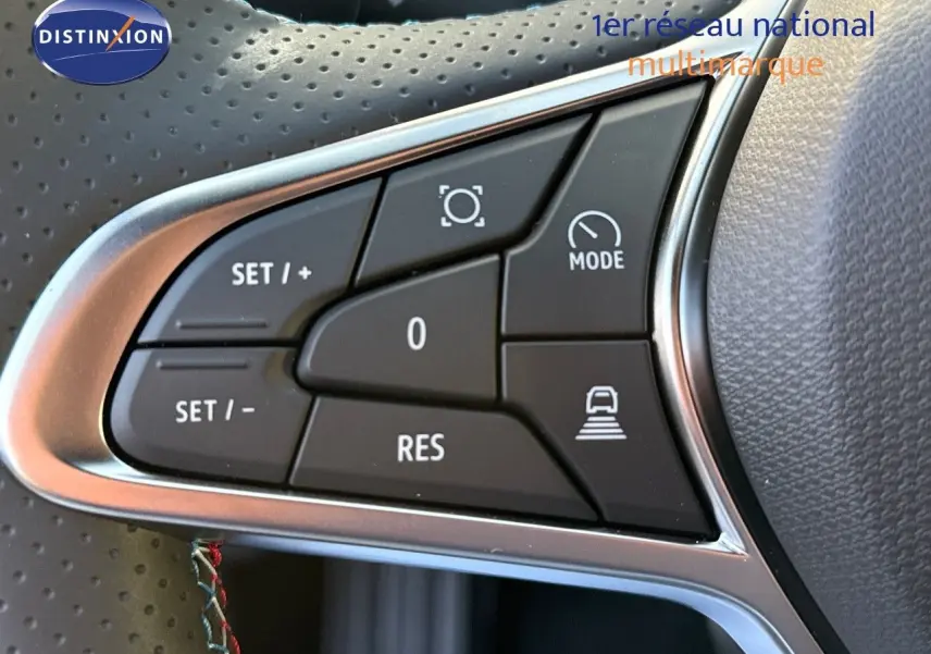 Gros plan sur les commandes de régulateur au volant en cuir perforé du Renault Symbioz gris cassiopée métal.