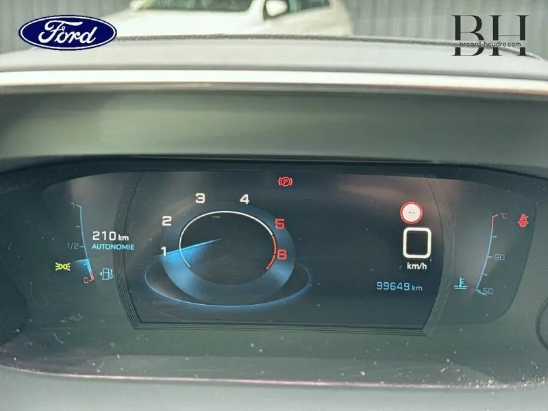 Tableau de bord numérique d'un Ford, affichant la vitesse, le compte-tours et l'autonomie de 210 km.