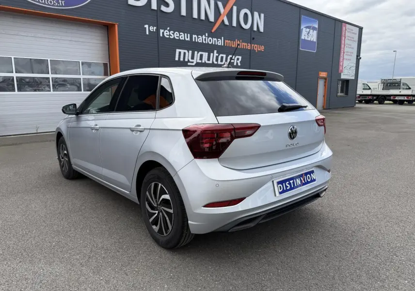 Volkswagen Polo gris reflet argent vue 3/4 arrière droit, avec vitres arrière surteintées et feux LED distinctifs.