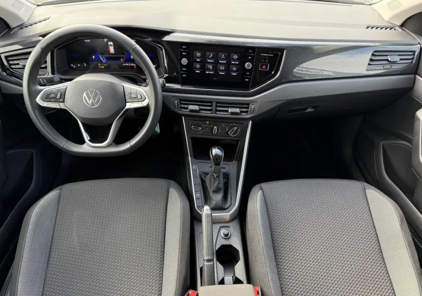 Vue intérieure avant du tableau de bord et des sièges gris de la Volkswagen Polo 2025 avec écran tactile et volant multifonction.