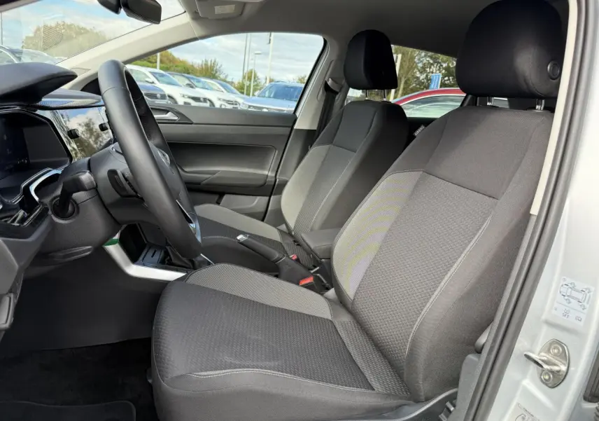 Vue intérieure côté conducteur de la Volkswagen Polo gris Reflet Argent, sièges tissu gris et tableau de bord moderne.