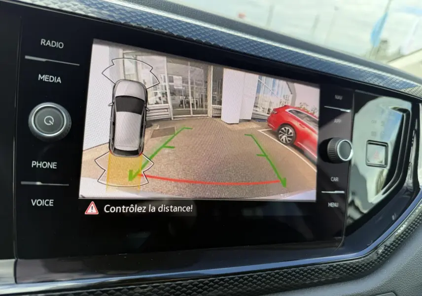 Affichage de la caméra de recul sur l'écran multimédia d'une Volkswagen Polo gris reflet argent, vue arrière avec marquages verts et rouges.