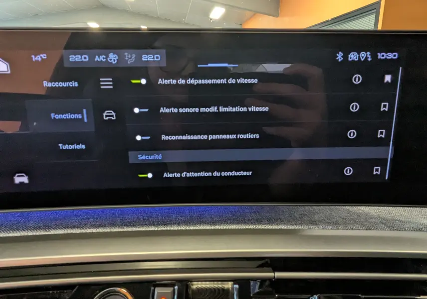 Vue rapprochée de l'écran tactile panoramique 21'' du Peugeot 3008 Hybrid noir, affichant les réglages de sécurité et climatisation.