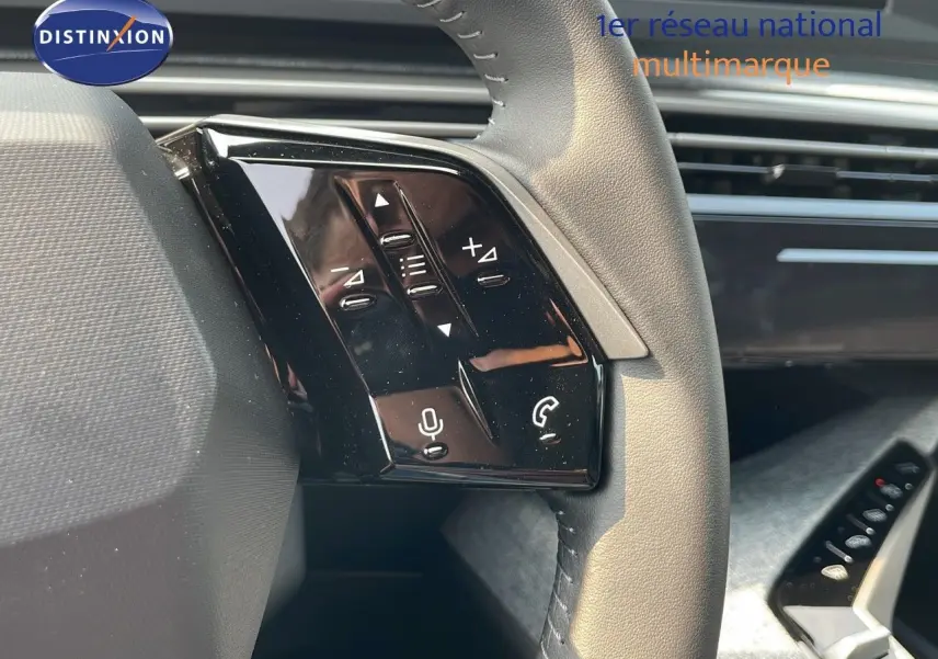 Gros plan sur les commandes gauche du volant cuir gris du Peugeot 3008 Hybrid 2025, avec boutons multifonctions.