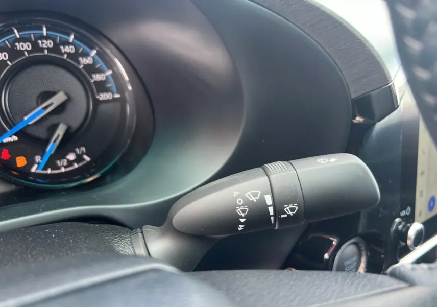 Gros plan sur la commande des essuie-glaces du Toyota Hilux 2025, tableau de bord et compteur partiellement visibles.