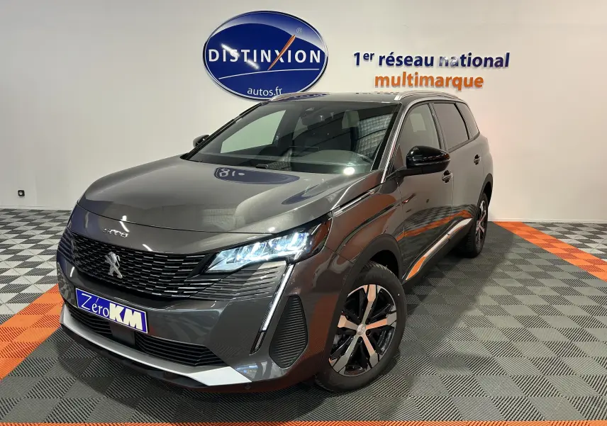 Peugeot 5008 Gris Platinium en 3/4 avant droit, avec phares LED allumés et jantes bi-ton visibles.