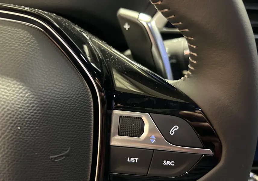 Gros plan sur les commandes gauche du volant du Peugeot 5008 2024, finition Allure Pack gris Platinium.