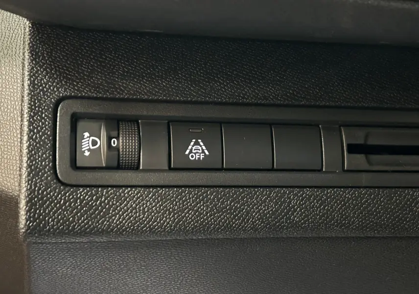 Gros plan sur les commandes de réglage des phares et de désactivation de l'alerte de franchissement de ligne dans un Peugeot 5008 gris Platinium 2024.