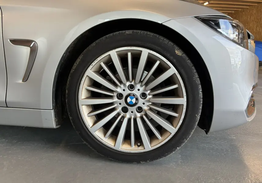 Gros plan sur la roue avant gauche gris clair d'une BMW Série 4 Cabriolet F33 avec jante multi-branches en aluminium.
