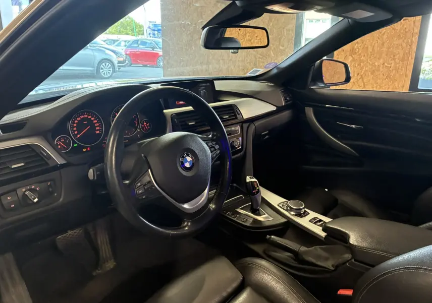 Intérieur noir de la BMW Série 4 Cabriolet 420i 2019, vue côté conducteur sur le tableau de bord et la console centrale.