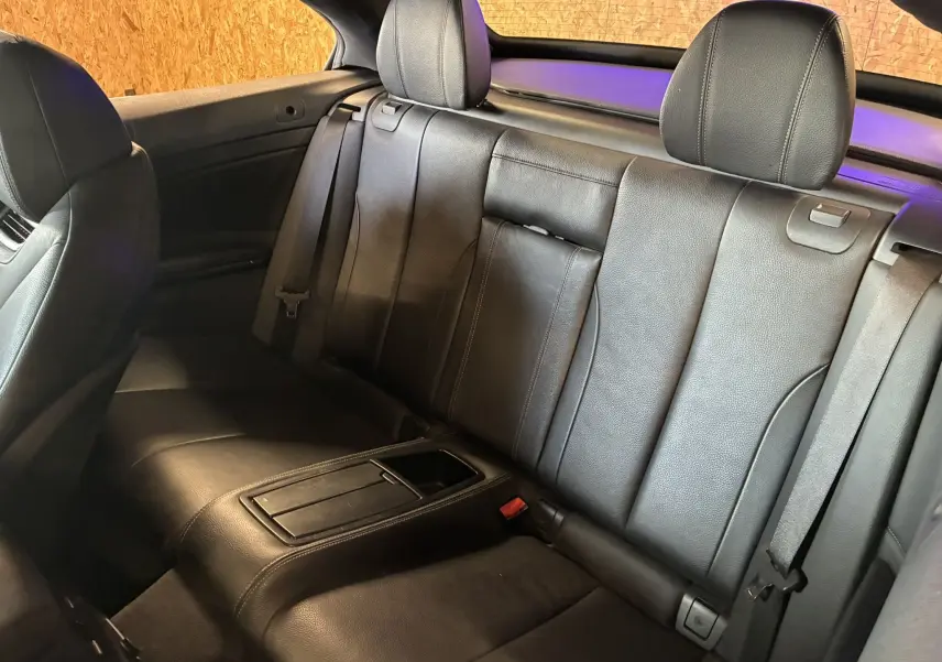 Vue intérieure arrière de la BMW Série 4 Cabriolet 420i 2019 avec sièges en cuir noir et accoudoir central fermé.