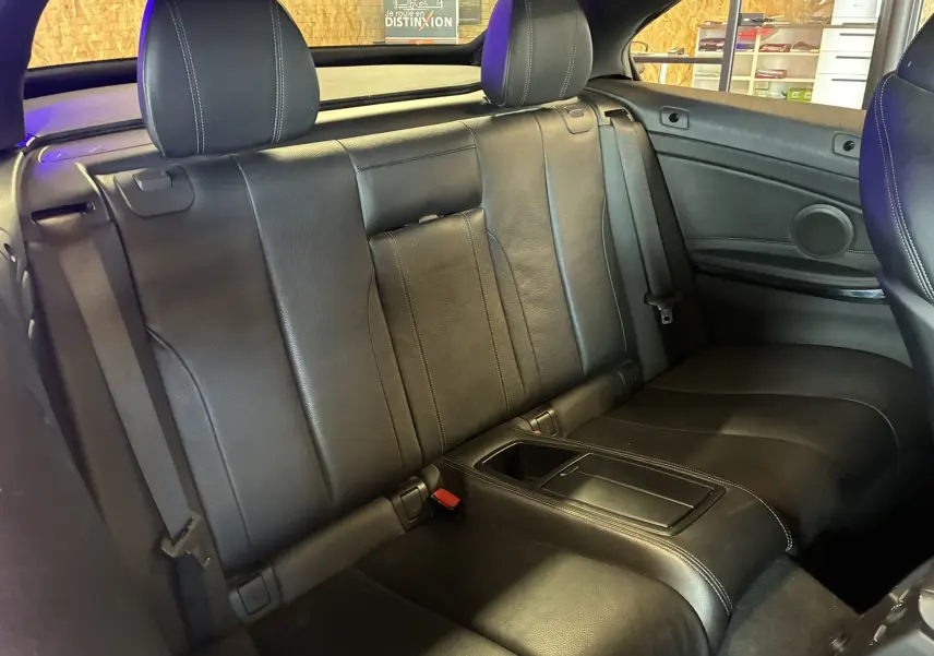 Vue intérieure arrière des sièges en cuir noir de la BMW Série 4 Cabriolet F33 gris, avec accoudoir central et appuie-têtes.