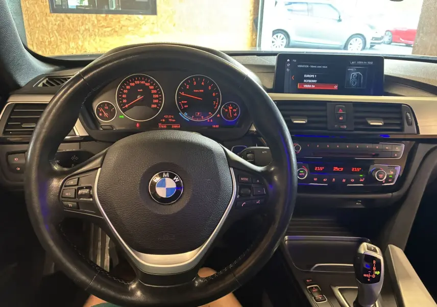 Vue intérieure centrée sur le volant cuir et le tableau de bord lumineux de la BMW Série 4 Cabriolet gris 2019.